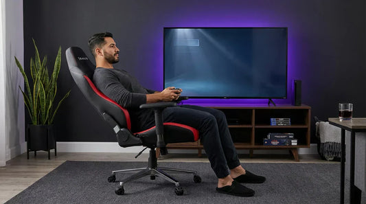 Gamer reclined in a black-and-red ergonomic gaming chair in front of a TV — recline angle for console gaming comfort